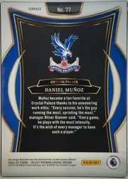 Back of 2024-25 Panini Select Premier League Soccer Daniel Muñoz #77 Terrace, upright portrait-oriented card back. A white outer border surrounds a blue, black, gold, and white decorative frame. The upper section shows the…
