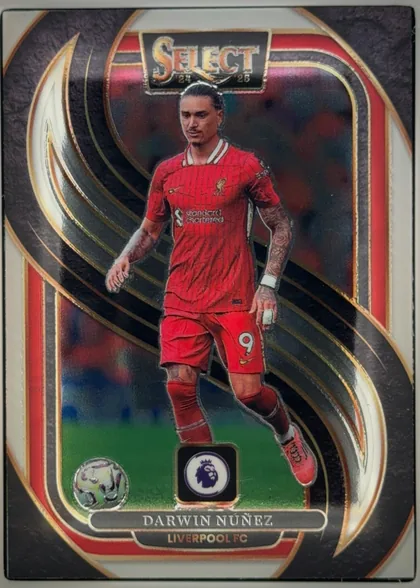 Front of 2024-25 Panini Select Premier League Soccer Darwin Núñez #142 Mezzanine, upright portrait soccer card. A full-body image of Darwin Núñez in a red Liverpool FC kit appears centrally over a dark abstract background with…