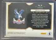 Back of 2024-25 Panini Select Premier League Soccer Eberechi Eze #16 Prizm, back of a soccer card. A dark charcoal rectangular panel dominates the upper and middle area, bordered by thin gold rules and rounded gold accents…