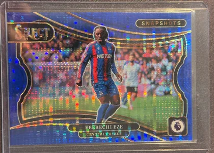 Front of 2024-25 Panini Select Premier League Soccer Eberechi Eze #16 Prizm, upright portrait soccer card front. A blue holographic design surrounds a central action photograph of Eberechi Eze in a Crystal Palace kit on a…