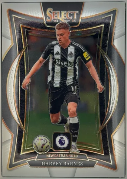 Front of 2024-25 Panini Select Premier League Soccer Harvey Barnes #89, upright portrait soccer card. A male footballer in a black-and-white Newcastle United kit is pictured running with a ball. The top has a large…