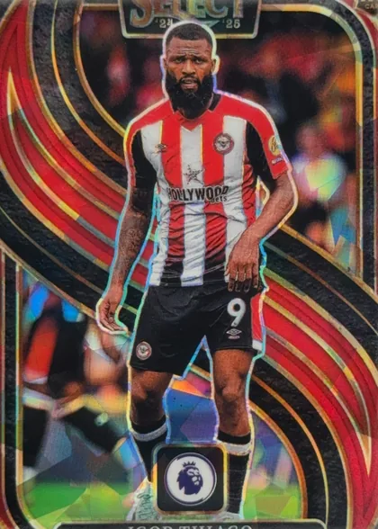 Front of 2024-25 Panini Select Premier League Soccer Igor Thiago #104 Mezzanine Prizm, front of a soccer card. A full-body die-cut photo of a bearded player in a red-and-white vertical striped Middlesbrough home shirt (Umbro logo…
