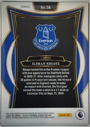 Back of 2024-25 Panini Select Premier League Soccer Iliman Ndiaye #58, upright portrait-oriented card back. A white margin surrounds an ornate black central panel bordered by gold lines, with large royal-blue curved…