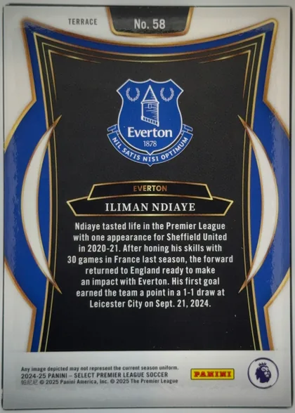 Back of 2024-25 Panini Select Premier League Soccer Iliman Ndiaye #58, upright portrait-oriented card back. A white margin surrounds an ornate black central panel bordered by gold lines, with large royal-blue curved…