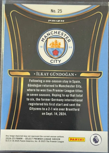 Back of 2024-25 Panini Select Premier League Soccer İLKAY GÜNDOĞAN #25 Prizm, upright portrait-oriented card back. A Manchester City crest is centered in the upper half within a black field framed by curved blue, gold, and…