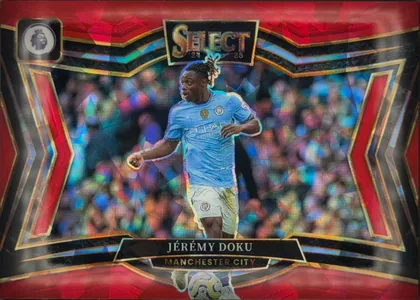 Front of 2024-25 Panini Select Premier League Soccer JÉRÉMY DOKU #222 Field Level Prizm, landscape soccer card front. A Manchester City player in a light blue kit is pictured running in front of a blurred stadium crowd with multicolored…