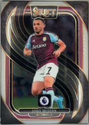 Front of 2024-25 Panini Select Premier League Soccer John McGinn #115 Mezzanine, front of a portrait soccer card. A large central action image shows John McGinn in an Aston Villa burgundy-and-light-blue kit. The upper center has…
