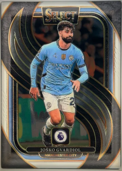 Front of 2024-25 Panini Select Premier League Soccer JOŠKO GVARDIOL #154 Mezzanine, portrait football card front. A full-body image of Josko Gvardiol in a light blue Manchester City kit is centered within an ornate black, blue, and…