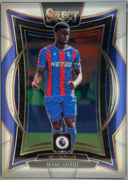 Front of 2024-25 Panini Select Premier League Soccer Marc Guéhi #78 Terrace, front of a portrait soccer card. A Crystal Palace player is shown standing in uniform against a dark stadium background. The SELECT 24/25 logo is…