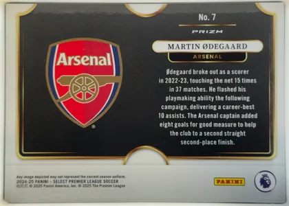 Back of 2024-25 Panini Select Premier League Soccer Martin Ødegaard #7 Silver Prizm, landscape-oriented card back. A large Arsenal crest occupies the left half of a black panel. On the right, a white rounded nameplate reads "MARTIN…