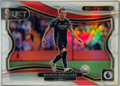 Front of 2024-25 Panini Select Premier League Soccer Martin Ødegaard #7 Silver Prizm, front soccer card featuring Martin Ødegaard in an Arsenal black away kit on a soccer pitch, with a blurred multicolor stadium background. The…