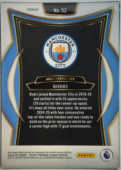 Back of 2024-25 Panini Select Premier League Soccer Rodri #52 Terrace, upright portrait-oriented card back. A white border surrounds an ornate blue, black, white, and gold frame. The Manchester City crest is centered…