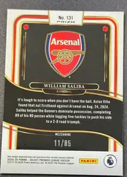 Back of 2024-25 Panini Select Premier League Soccer William Saliba #131 Mezzanine /85, serial numbered 11/85, upright landscape-oriented card back with a white border and ornate red, gold, and black curved framing. The upper center has a white tab reading…