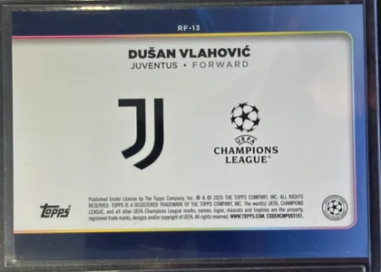 Back of 2024-25 Topps UEFA Club Competitions Soccer DUŠAN VLAHOVIĆ #RF-13 Trophy Chasers, back of a portrait-oriented soccer card. A dark blue outer field frames a large white rounded-rectangle panel. RF-13 is centered near the top. The…