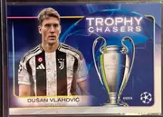 Front of 2024-25 Topps UEFA Club Competitions Soccer DUŠAN VLAHOVIĆ #RF-13 Trophy Chasers, upright landscape soccer card front. A portrait of Dušan Vlahović in a Juventus black-and-white kit occupies the left side. A large UEFA Champions…