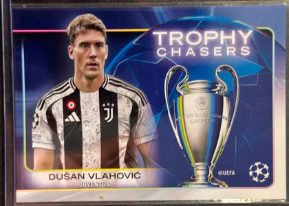 Front of 2024-25 Topps UEFA Club Competitions Soccer DUŠAN VLAHOVIĆ #RF-13 Trophy Chasers, upright landscape soccer card front. A portrait of Dušan Vlahović in a Juventus black-and-white kit occupies the left side. A large UEFA Champions…