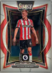 Front of 2024 Panini Select Premier League Flynn Downes #47, front-facing portrait football card. A large stylized SELECT 24 25 logo is centered at the top. Flynn Downes is shown in a Southampton red-and-white…