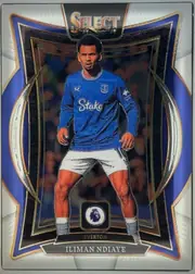 Front of 2024 Panini Select Premier League Iliman Ndiaye #58 Base Set Premier League Terrace, portrait-oriented football card front. A player in an Everton blue kit is centered within an ornate black, blue, gold, and silver geometric frame…