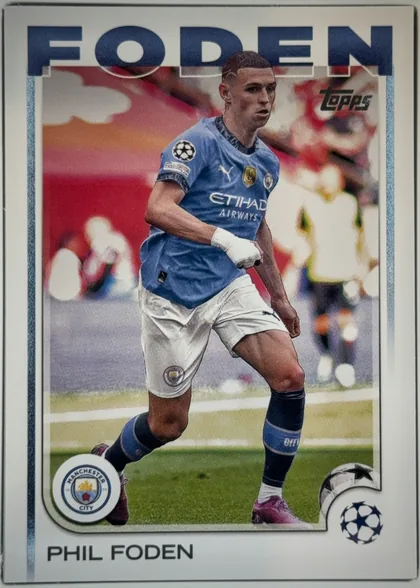 Front of 2024 Topps UEFA Phil Foden #47 Base, front of a soccer card. Across the top, the surname 'FODEN' is printed in very large bold dark-blue sans-serif capital letters. Below it is a…