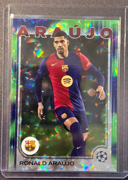 Front of 2024 Topps UEFA Ronald Araújo #24 Base, portrait soccer card front. Large red uppercase ARAUJO text spans the top. A player in an FC Barcelona red-and-blue kit is shown centrally against a…