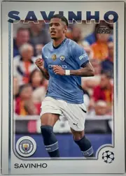 Front of 2024 Topps UEFA Savinho #56 Base, front of a soccer card. A large dark-blue sans-serif name 'SAVINHO' spans the top, partially overlapping the top of the photo. The central photo…
