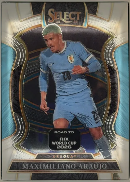 Front of 2025-26 Panini - Select Road to FIFA World Cup 2026 Soccer MAXIMILIANO ARAÚJO #17 Terrace, upright portrait soccer card front. The top center displays the SELECT logo with "25 26" beneath it. A soccer player in a light blue Uruguay kit is…