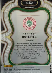 Back of 2025-26 Panini - Select Road to FIFA World Cup 2026 Soccer Raphael Onyedika #122 Mezzanine, upright portrait-oriented card back. A black top plaque with gold trim holds "No. 122" and "MEZZANINE." The body is a light gray/cream panel framed…