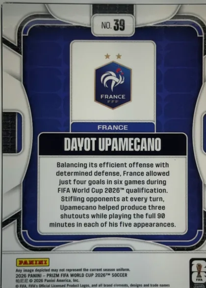 Back of 2026 Panini Prizm FIFA Dayot Upamecano #39 Base, portrait-oriented soccer card back. A blue patterned central panel is surrounded by a white and black geometric border. At the top center is a white…