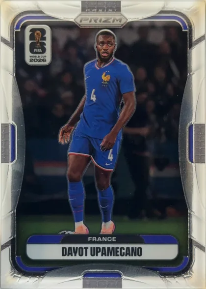 Front of 2026 Panini Prizm FIFA Dayot Upamecano #39 Base, portrait soccer card front. A full-body image of Dayot Upamecano in a blue France kit occupies the center against a dark stadium background. The…
