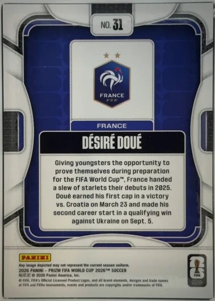 Back of 2026 Panini Prizm FIFA DÉSIRÉ DOUÉ #31 Base, upright portrait-format card back. A white and silver geometric outer design surrounds a dark blue inset panel with rounded corners and thin black…