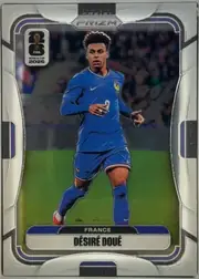 Front of 2026 Panini Prizm FIFA DÉSIRÉ DOUÉ #31 Base, portrait-oriented soccer card front. A full-body image of a France player in a blue kit occupies the center against a stadium background. The…