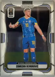 Front of 2026 Panini Prizm FIFA Ermedin Demirović #470 Base, portrait-format soccer card front. A full-body image of Ermedin Demirović in a blue Bosnia-Herzegovina kit occupies the center against a dark…