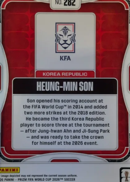 Back of 2026 Panini Prizm FIFA HEUNG-MIN SON #282 Base, upright landscape-oriented card back. A red geometric patterned field is enclosed by white rounded border lines. At the top center is a white label…