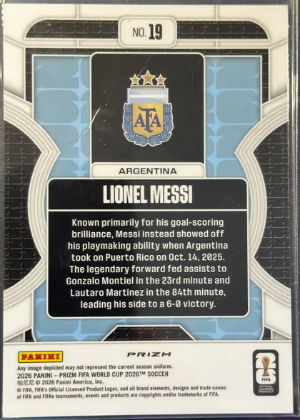 Back of 2026 Panini Prizm FIFA Phenomenon Lionel Messi #19, upright portrait-oriented card back. A white top panel contains the centered card number "NO. 19". Below it is an Argentina crest in a black…