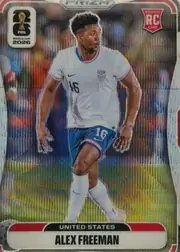 Front of 2026 Panini Prizm FIFA Soccer Cards Alex Freeman #433 Prizm (refractor), front of a soccer card. A full-body action photo of a male player in a white USA jersey (number 16) and blue shorts (number 16) with white socks…