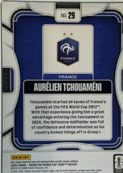 Back of 2026 Panini Prizm FIFA Soccer Cards AURÉLIEN TCHOUAMÉNI #29, portrait-oriented player card back. A dark blue rounded rectangular panel with white and metallic-silver decorative framing fills most of the card…
