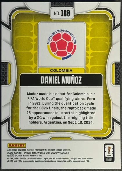 Back of 2026 Panini Prizm FIFA Soccer Cards Daniel Muñoz #180, portrait-oriented card back. The number “NO. 180” is centered near the top. A Colombia federation crest appears in a white panel above a yellow…