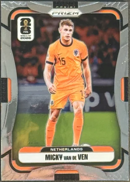 Front of 2026 Panini Prizm FIFA Soccer Cards Micky van de Ven #316, portrait soccer card front. A Netherlands player in an orange national-team uniform is pictured centrally on a soccer-field background. The card has…