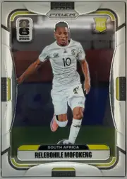 Front of 2026 Panini Prizm FIFA Soccer Cards Relebohile Mofokeng #410, portrait soccer card front featuring Relebohile Mofokeng in a white South Africa kit running with a ball. A PRIZM logo is centered at the top, the…