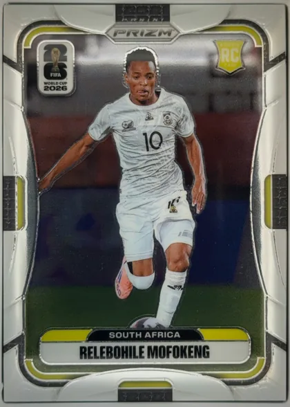 Front of 2026 Panini Prizm FIFA Soccer Cards Relebohile Mofokeng #410, portrait soccer card front featuring Relebohile Mofokeng in a white South Africa kit running with a ball. A PRIZM logo is centered at the top, the…