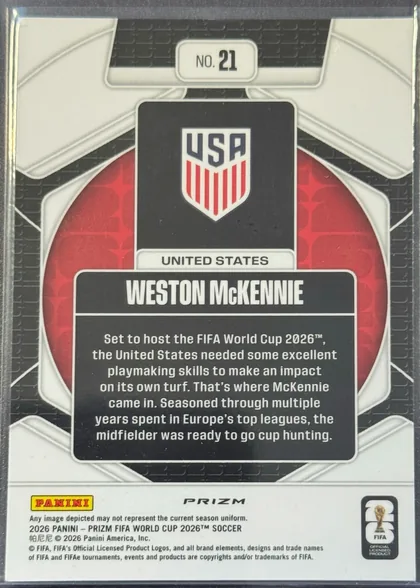 Back of 2026 Panini Prizm FIFA Trophy Hunting Weston McKennie #21, upright portrait-format card back. A black-and-white geometric soccer design surrounds a red circular center. At the top is a white plaque reading…