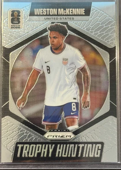 Front of 2026 Panini Prizm FIFA Trophy Hunting Weston McKennie #21, portrait-oriented soccer card front. The player's name appears in large white uppercase lettering on a black banner at the top, with UNITED STATES…
