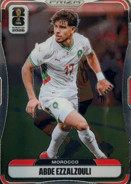 Front of 2026 Panini Prizm FIFA World Cup Soccer ABDE EZZALZOULI #302, portrait soccer card front. A male soccer player in a white Morocco kit is shown running against a dark stadium background. The top center has a…