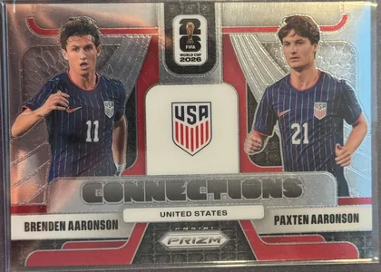 Front of 2026 Panini Prizm FIFA World Cup Soccer Brenden Aaronson and Paxten Aaronson #5, upright portrait-oriented soccer card front featuring Brenden Aaronson on the left and Paxten Aaronson on the right in United States navy uniforms…