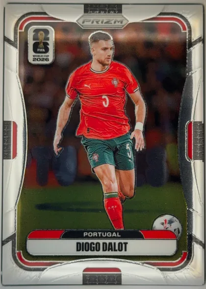 Front of 2026 Panini Prizm FIFA World Cup Soccer Diogo Dalot Base, upright portrait soccer card. A Portugal player in a red jersey and green shorts is shown running with a ball on a field. The top center has PANINI…