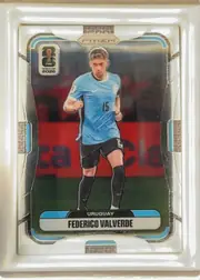Front of 2026 Panini Prizm FIFA World Cup Soccer Federico Valverde, portrait soccer card front. A player in a light blue Uruguay uniform runs centrally against a stadium background. The PRIZM logo is centered near…