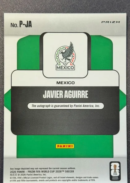 Back of 2026 Panini Prizm FIFA World Cup Soccer Javier Aguirre #P-UA Penmanship autographed, upright card back with a white background and green geometric side panels. "No. P-UA" is printed at the upper left and "PRIZM" at the upper right. A…