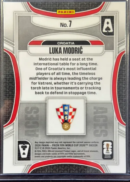 Back of 2026 Panini Prizm FIFA World Cup Soccer Luka Modrić #7, back of a portrait-format soccer card. A yellow PANINI logo is centered near the top above the card number "No. 7". The upper-middle black nameplate…