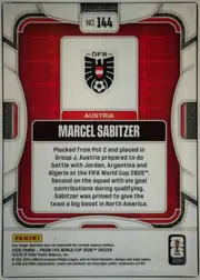 Back of 2026 Panini Prizm FIFA World Cup Soccer Marcel Sabitzer #144 Base, upright portrait-oriented card back. A large red patterned central panel is framed by white, gray, and black geometric borders. Near the top center…