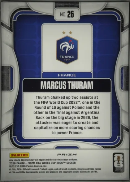 Back of 2026 Panini Prizm FIFA World Cup Soccer Marcus Thuram #26, upright portrait-format card back. A white and gray outer design frames a dark blue central panel with rounded layered borders. The top center has a…